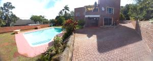 a swimming pool in front of a house at Rilli's Inn Apartment in Mtunzini