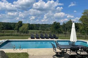 a pool with a table and chairs and an umbrella at Beautifully restored five bedroom historic barn in Oakwood