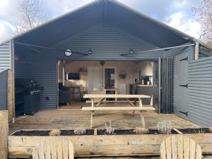 a blue shed with a picnic table on a wooden deck at Sumners Ponds Fishery & Campsite in Horsham