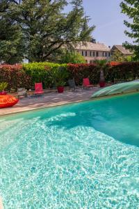 a large swimming pool with red chairs in a yard at Le Clos d'Albray - Chambres d'hôtes et gite in Comps-la-Grand-Ville
