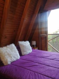 a bedroom with a purple bed with a large window at Per a Tu in Punta del Este