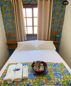 a bed with two towels and a basket of toys on it at POUSADA MORADAS DO JAU in Hermenegildo