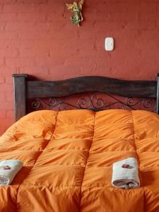 Una cama naranja con dos toallas encima. en Finca Hotel alto de la gloria Filandia La tierra del encanto en Filandia