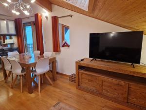 ein Esszimmer mit einem großen TV und einem Tisch in der Unterkunft Appartement tout confort montagne et lac Léman in Thollon