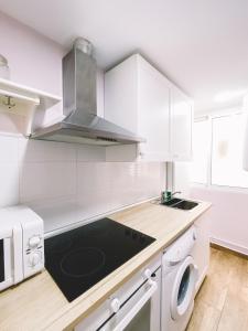 a kitchen with white cabinets and a stove top oven at Home Málaga in Málaga