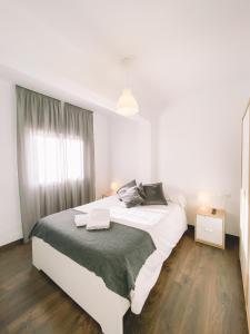 a white bedroom with a large bed and a window at Home Málaga in Málaga