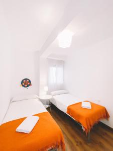 two beds in a white room with orange sheets at Home Málaga in Málaga