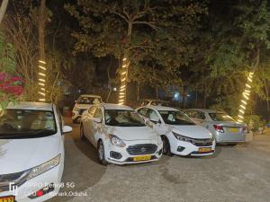 eine Reihe weißer Autos auf einem Parkplatz in der Unterkunft Labanya Lodge in Konark