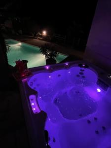 a purple bathtub with lights in front of a pool at Chambre au calme avec spa privatif gratuit sud aveyron les palmiers des causses in Saint-Rome-de-Tarn