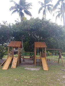a playground with two wooden benches and palm trees at LINDO Flat Eco Resort - melhor trecho da praia de Carneiros in Praia dos Carneiros