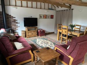 a living room with two couches and a table at Wood Farm Barn in Laxfield