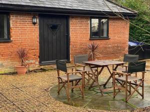 a wooden table and chairs in front of a brick house at Wood Farm Barn in Laxfield