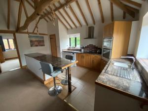 a kitchen with a table and a chair in it at Wood Farm Barn in Laxfield