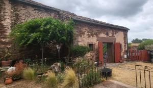 un edificio de ladrillo con una puerta roja y un árbol en La Boriette du Rougier, en Montlaur
