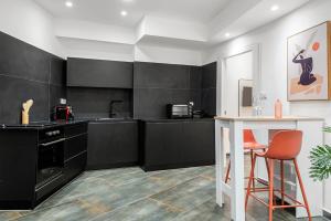 a kitchen with black cabinets and a table and a stool at Cozy New Space w Bomb Shelter steps from beach M7 in Tel Aviv +8 photos