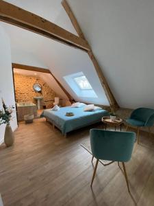 a attic bedroom with a bed and a chair at Sophie LE FEUVRE - Soins Energétiques in Baugé-en-Anjou