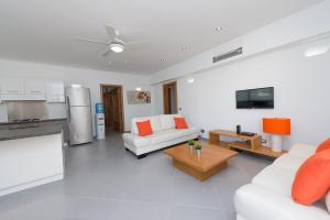 a living room with two white couches and a kitchen at Aligio Apart-hotel & Spa - Las Terrenas in Las Terrenas
