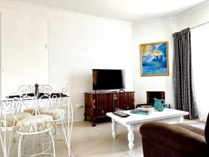 uma sala de estar com um sofá e uma televisão em Eucalyptus Cottage em Cidade do Cabo