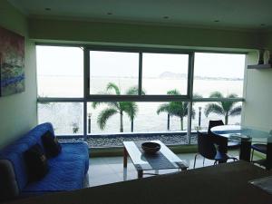 sala de estar con sofá azul y ventana grande en Apartments Puerto Santa Ana, en Guayaquil
