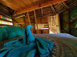 a bed with a blue blanket on top of it at Derek's Place Eco-Lodge in Little Corn Island