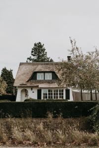 een wit huis met een rieten dak bij Charmeverblijf Juliette in Kasterlee