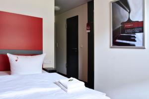 Dormitorio con cama blanca y póster en la pared en Hotel VielHarmonie, en Jena