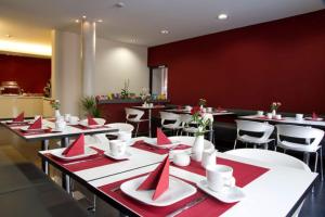 a restaurant with tables and chairs with red napkins on them at Hotel VielHarmonie in Jena