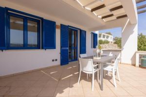 patio ze stołem, krzesłami i niebieskimi oknami w obiekcie Appartamenti Marinelli - Santa Maria di Leuca w mieście Leuca