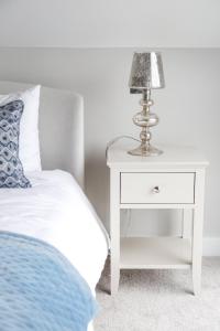 a white bedside table with a lamp on it at Ocean View - Bracklesham Bay in Chichester