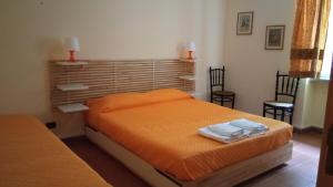 1 dormitorio con 1 cama con sábanas de color naranja y 2 sillas en B&B Al Boschetto, en Nemoli