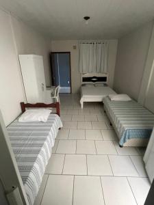 two beds in a small room with a window at Pousada carioca in São João da Barra
