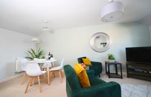 a living room with two green chairs and a table at Ideal Coach House in Swindon