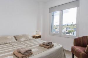 Un dormitorio blanco con una cama con toallas. en Walanika Apartamentos en Ushuaia