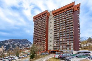 a tall building with cars parked in a parking lot at Les Laurentides in Villarembert