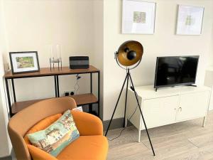 a living room with a chair and a flat screen tv at The Four Bays Apartment - Cliftonville Central - By Goldex Coastal Breaks in Kent