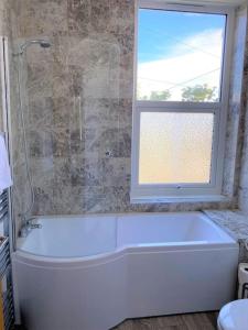 a white bath tub in a bathroom with a window at The Four Bays Apartment - Cliftonville Central - By Goldex Coastal Breaks in Kent