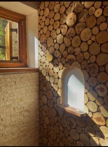 a wall with a pile of logs in a room with a window at Apartmani Astra in Risovac
