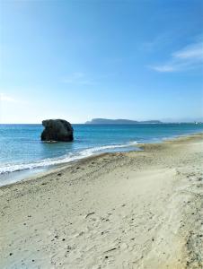 una playa con una gran roca en el agua en La piuma, en Quartu SantʼElena