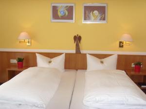 
a bed with two pillows and two pictures on the wall at Hotel & Restaurant Engel in Herbertingen
