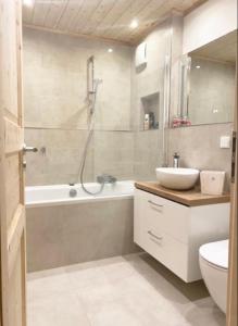 een badkamer met een bad, een wastafel en een douche bij FeWo Alpenwiese mit Hallenbad&Sauna in Missen-Wilhams