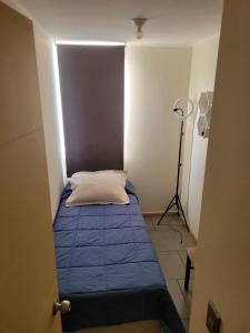 une petite chambre avec un lit bleu et une lampe dans l'établissement Departamento en Curicó, à Curicó