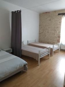1 dormitorio con 2 camas y pared de ladrillo en LA LAUJÈRE IVIE - Gîte & Piscine privative, en Saint-Hilaire-du-Bois