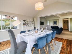 a dining room with a table and blue chairs at Glenhurst in Dronfield