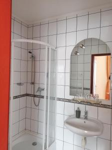 een badkamer met een douche, een wastafel en een spiegel bij Medgyaszay Panzió in Nagykanizsa