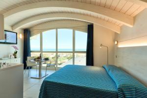 sypialnia z niebieskim łóżkiem i widokiem na ocean w obiekcie JUST SUITES w mieście Cervia