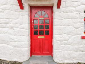 eine rote Tür in einem weißen Backsteingebäude in der Unterkunft Ti Sonny in Glinsk