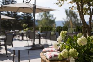 un patio con mesas, sillas, flores y una sombrilla en Hotel Salten, en Avelengo
