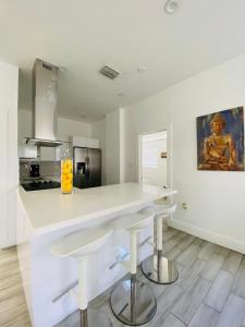 a white kitchen with a counter and stools at Modern & New,Excellent Location Miami in Miami