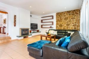 Una sala de estar con un sofá de cuero y una chimenea. en Villa Sa Tanca Den Lloses, en Can Furnet