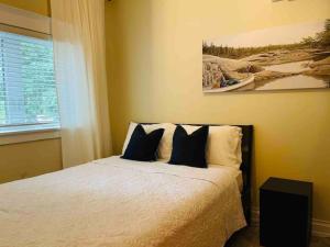 a bedroom with a bed with black and white pillows at SouthLake Cottage on The Lake. in Washago